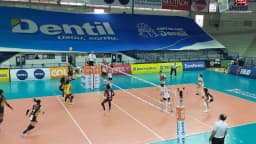 Jogadoras do Praia Clube em quadra durante partida da Superliga, com banner do patrocinador Dentil ao fundo