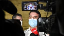 Flávio Bolsonaro é entrevistado por jornalistas, cercado de microfones