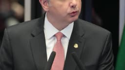 Rodrigo Pacheco discursa em podium com a bandeira do Brasil ao fundo