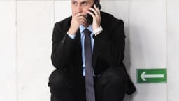 Cleitinho Azevedo fala ao telefone agachado em corredor do Senado Federal
