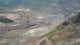 Vista aérea de mina de ferro a céu aberto em Itabira, Minas Gerais, com bancadas escavadas e caminhões de carga; foto de arquivo