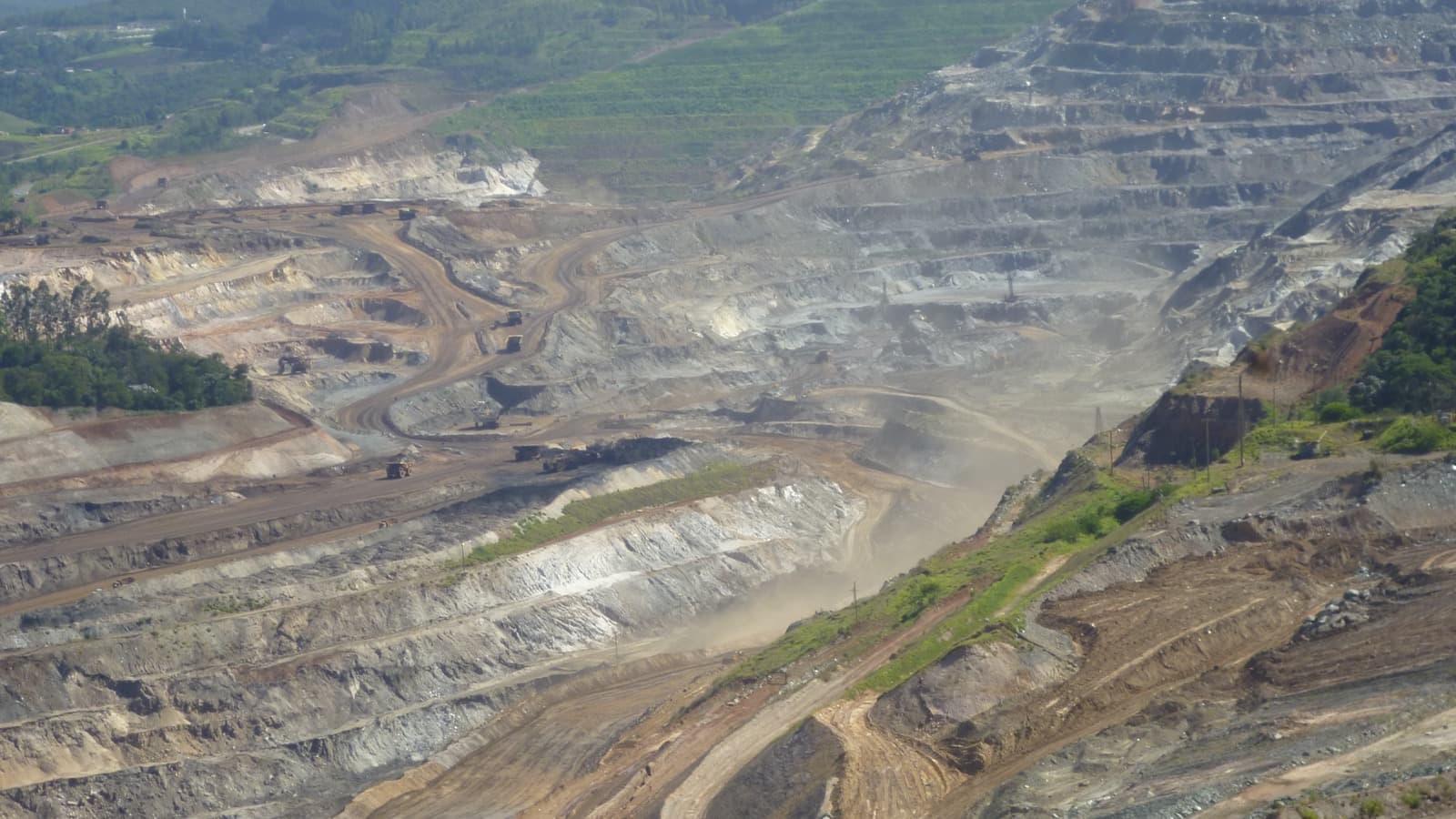 Vista aérea de mina de ferro a céu aberto em Itabira, Minas Gerais, com bancadas escavadas e caminhões de carga; foto de arquivo