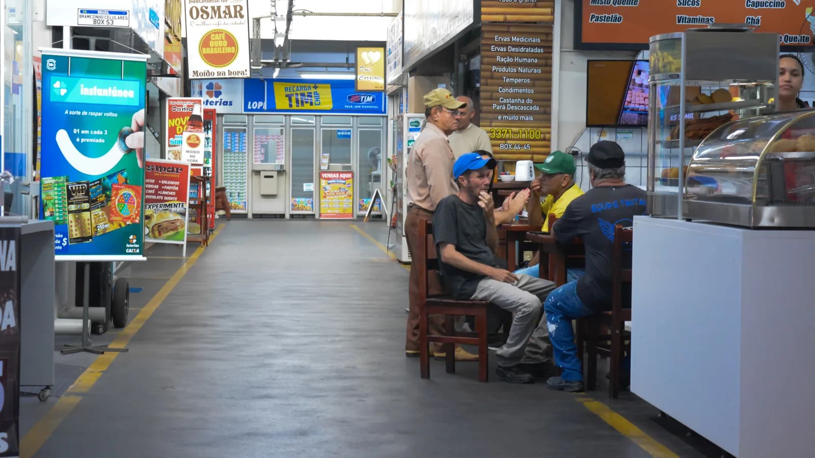 Pessoas sentadas comendo em mesas de uma cafeteria de mercado municipal
