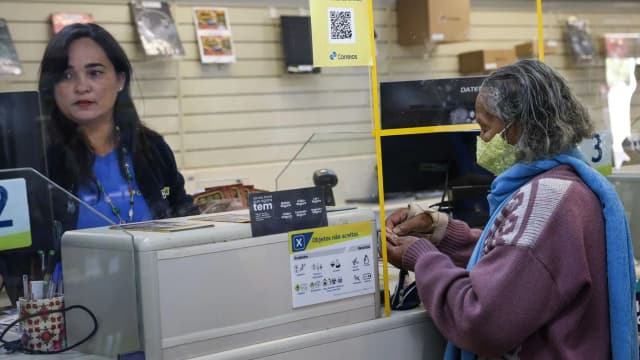 Idosa é atendida em guichê de atendimento sobre o INSS em agência dos Correios