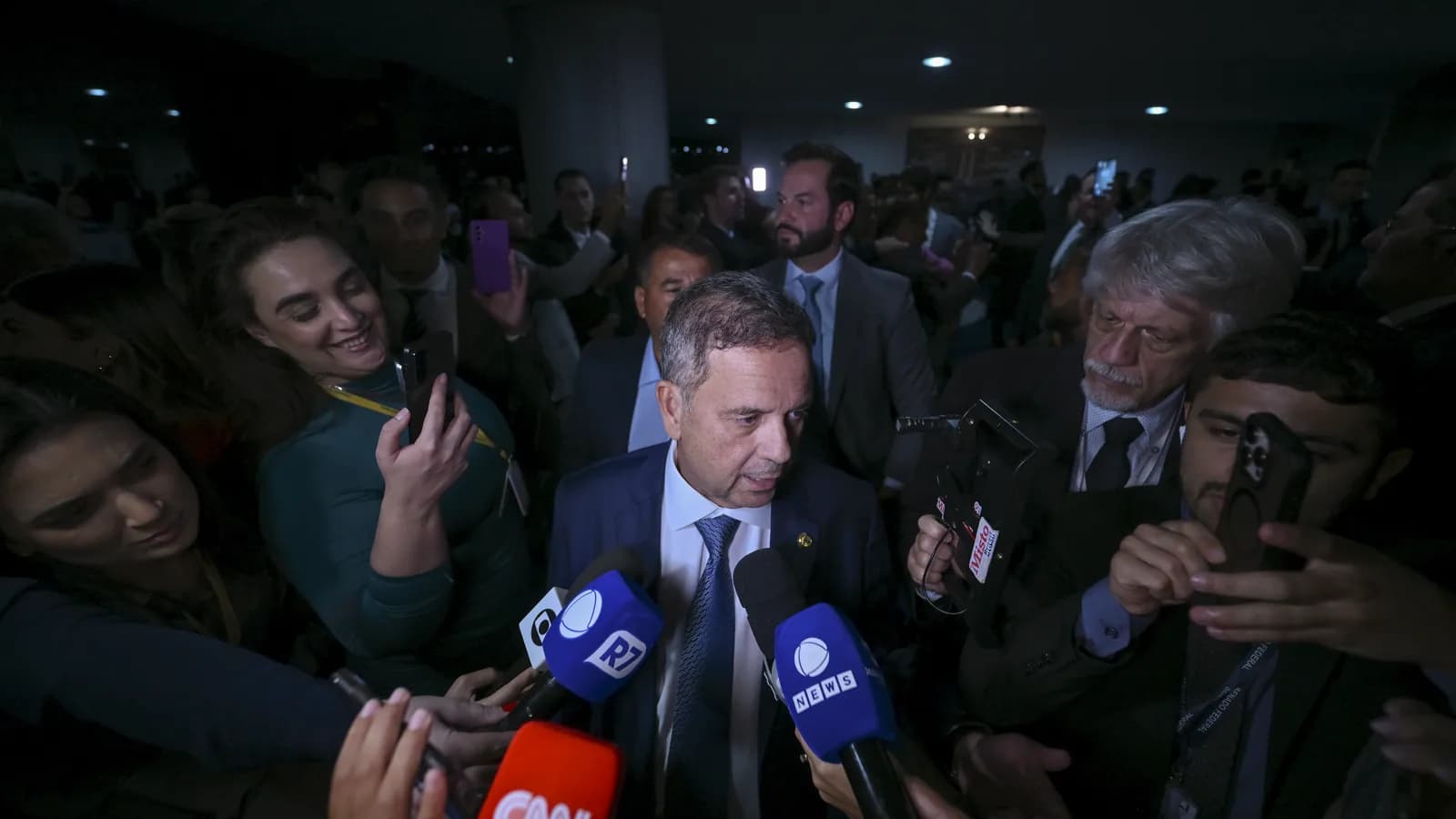 O senador Rogério Marinho, de terno azul, cercado por microfones de emissoras durante entrevista coletiva no Senado