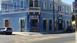 Fachada de agência da Caixa Econômica Federal em prédio histórico azul, com logo da Caixa na entrada