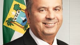 Retrato oficial do senador Rogério Marinho sorrindo diante da bandeira do Rio Grande do Norte