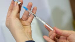 Mãos preparando uma seringa com dose de vacina para aplicação