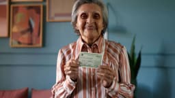 Eleitora idosa sorri ao mostrar o título de eleitor (foto de arquivo)