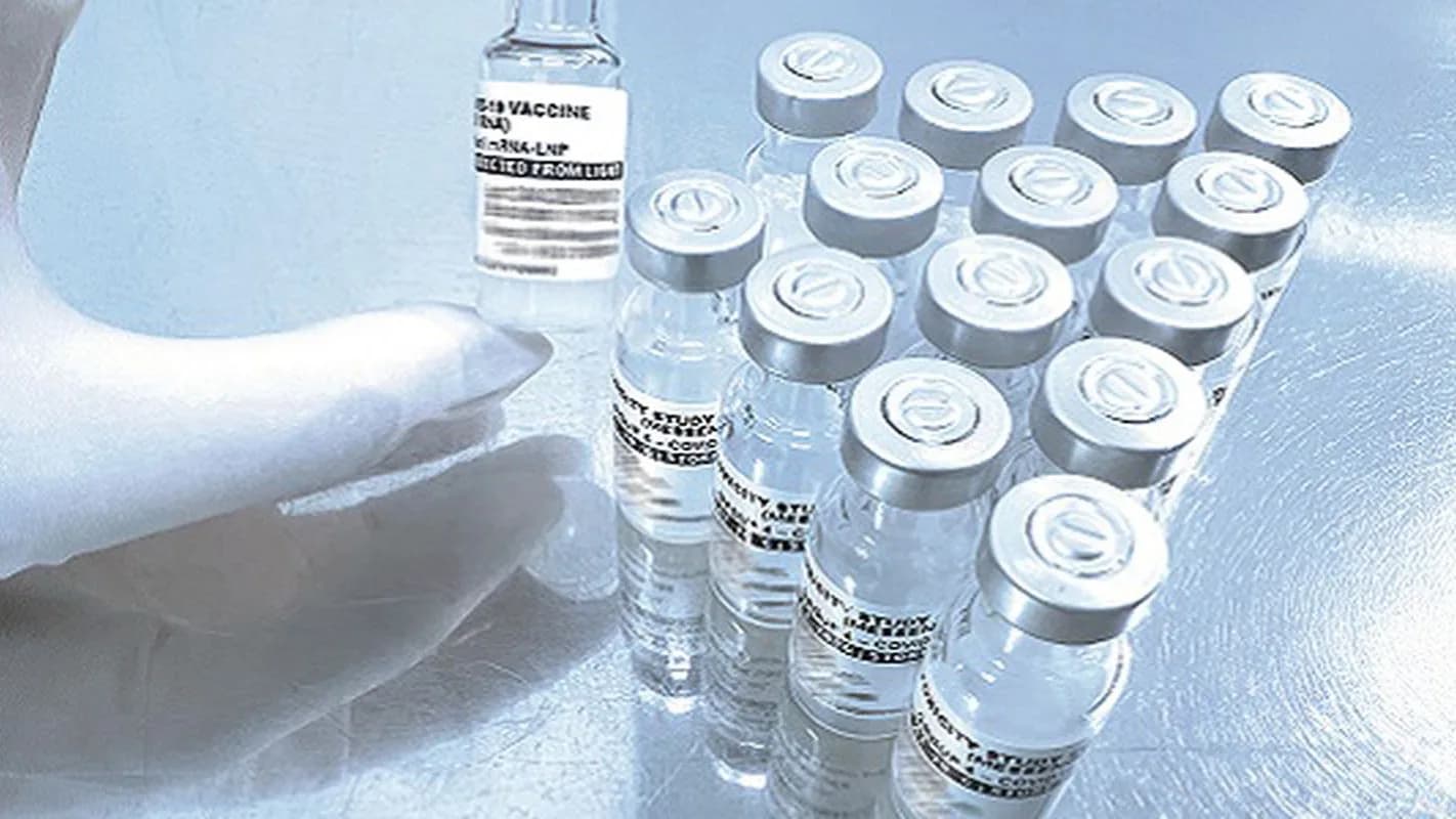 Mão com luva segura frasco de vacina contra Covid-19 de RNA mensageiro ao lado de outros frascos do estudo de estabilidade da Fiocruz