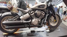 Moto custom Benda Napoleonbob exposta sobre plataforma em salão de motocicletas, com visitantes circulando ao fundo