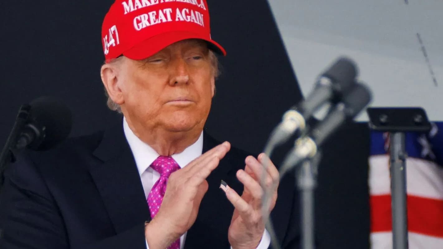Donald Trump discursa em evento de campanha com boné vermelho ao microfone