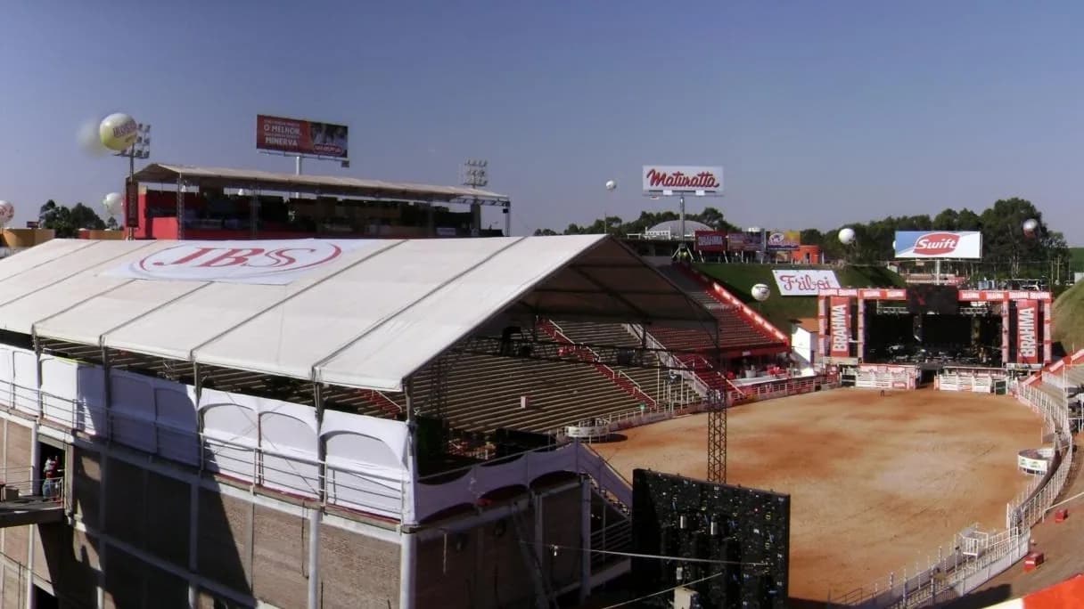 Arena de rodeio vista de cima, com arquibancadas e telão ao fundo