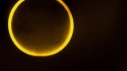 Eclipse solar anular visto como anel dourado no céu noturno