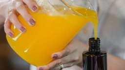 Produção artesanal de cosmético, com líquido sendo despejado em frasco