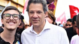 Fernando Haddad em ato de campanha, cercado por apoiadores e bandeiras do PT