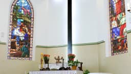 Interior de igreja evangélica luterana, com cruz iluminada e vitrais, foto ilustrativa de templo religioso