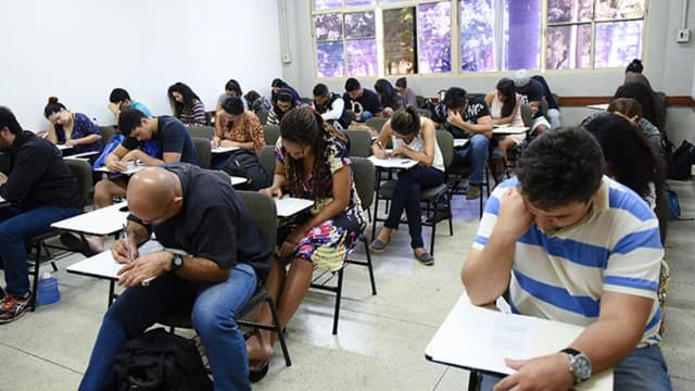 Candidatos adultos fazendo prova em sala de aula