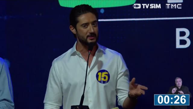 Gabriel Azevedo, candidato ao governo de Minas Gerais com o número 15, fala ao microfone em púlpito do debate, com cronômetro de 30 segundos na tela