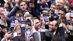 Flávio Bolsonaro sorri em meio a parlamentares que comemoram na Câmara dos Deputados, em abril de 2026