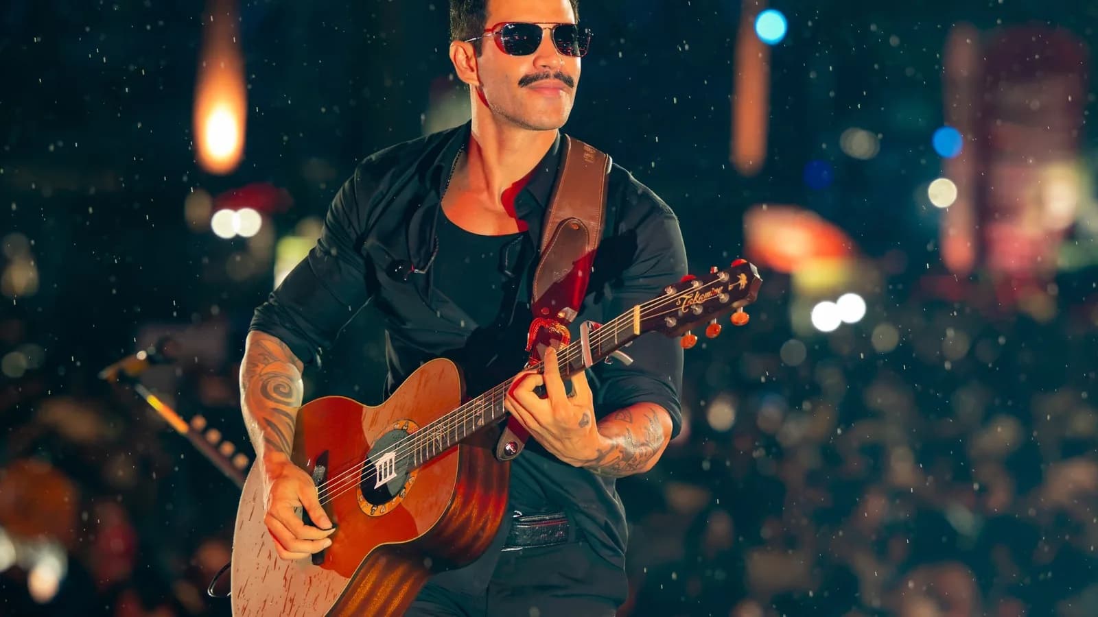 Gusttavo Lima toca violão em show com plateia ao fundo