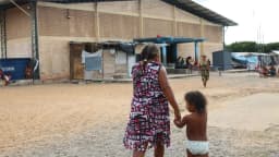 Mulher e criança caminham em abrigo improvisado para refugiados venezuelanos em Roraima