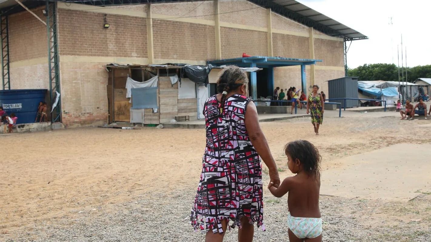 Mulher e criança caminham em abrigo improvisado para refugiados venezuelanos em Roraima
