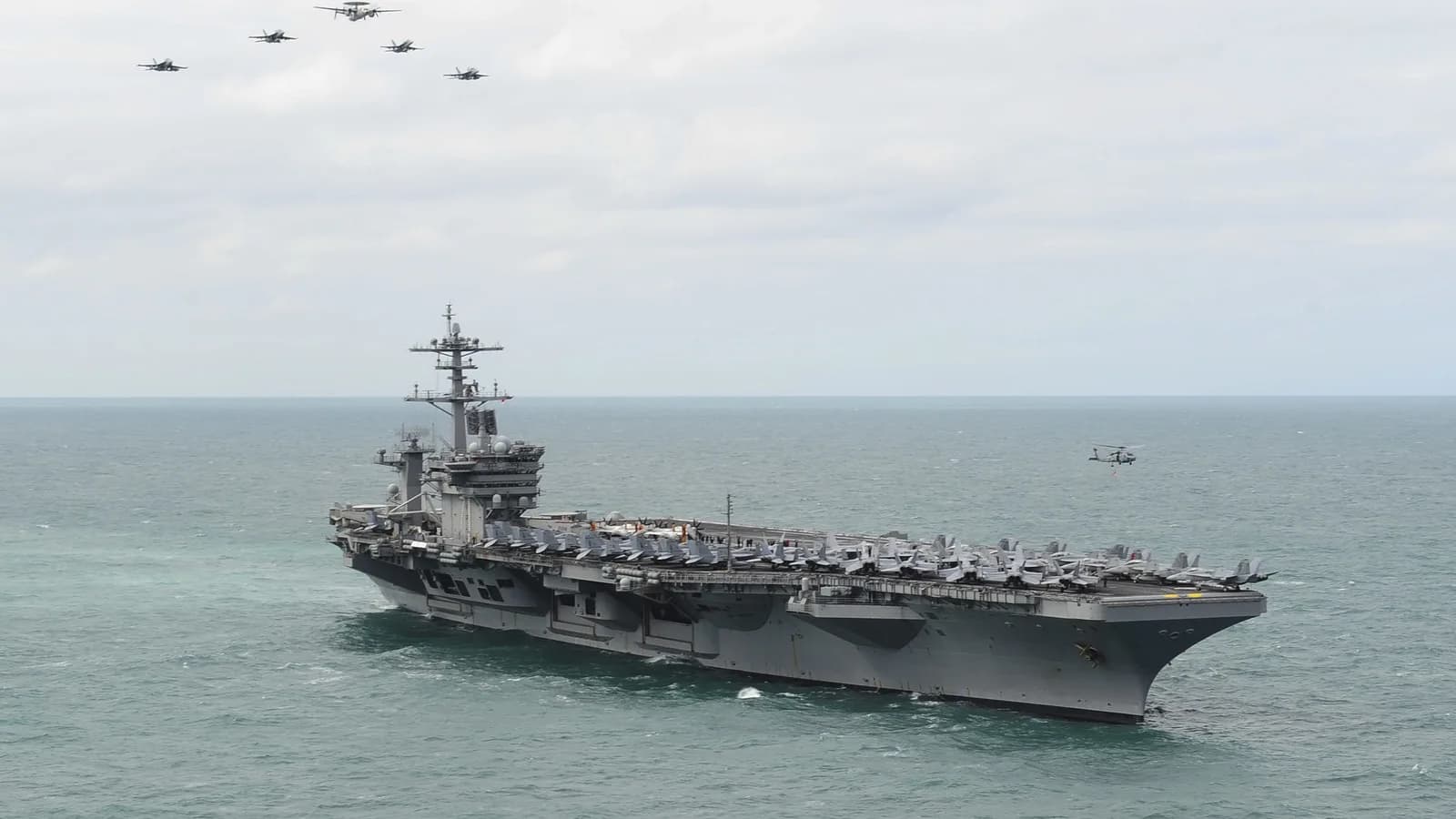 Porta-aviões USS Theodore Roosevelt navegando em alto-mar com aeronaves no convés