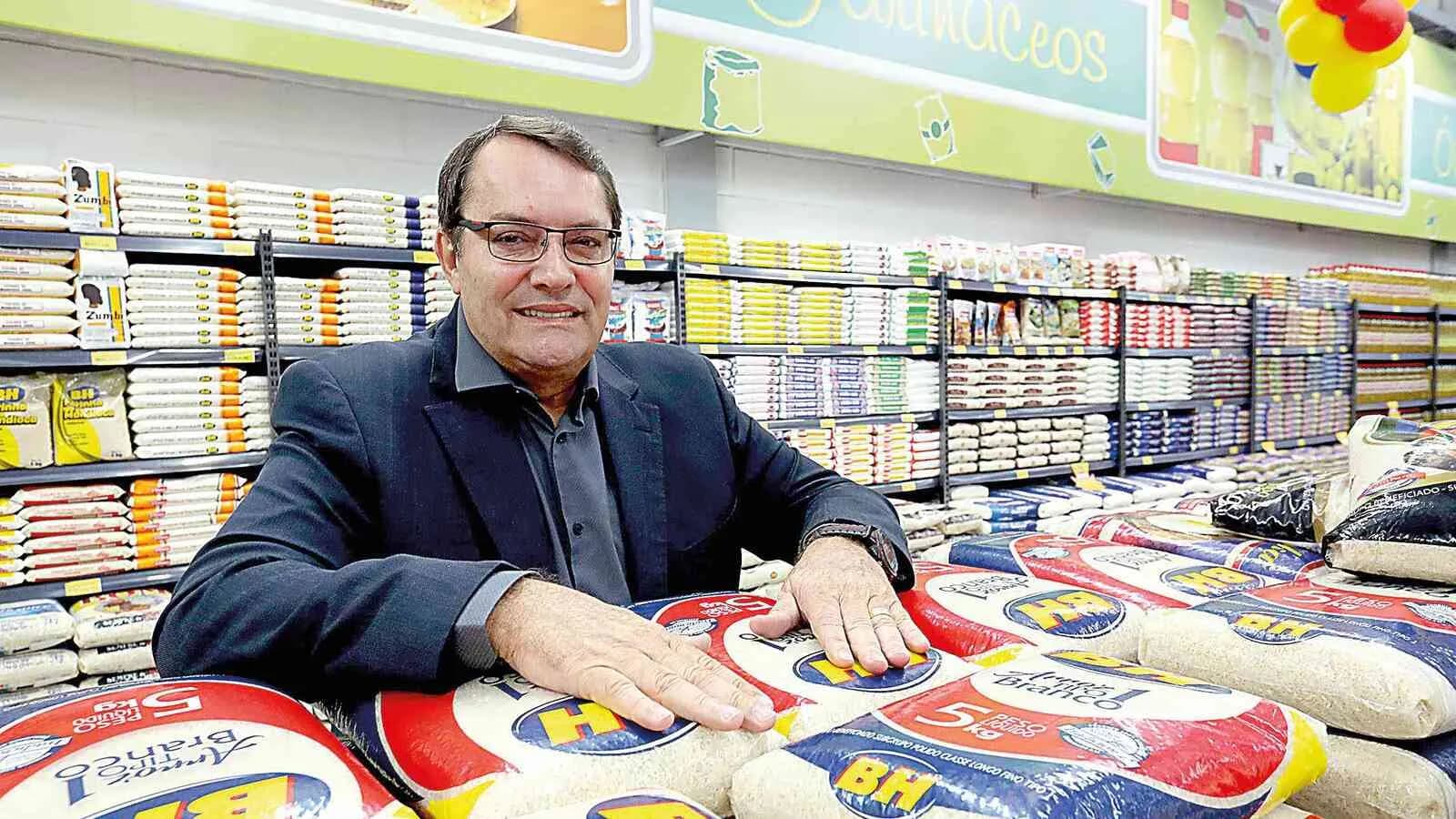 Pedro Lourenço em loja do Supermercados BH, cercado por sacas de arroz