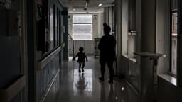 Corredor de hospital infantil com criança e acompanhante ao fundo