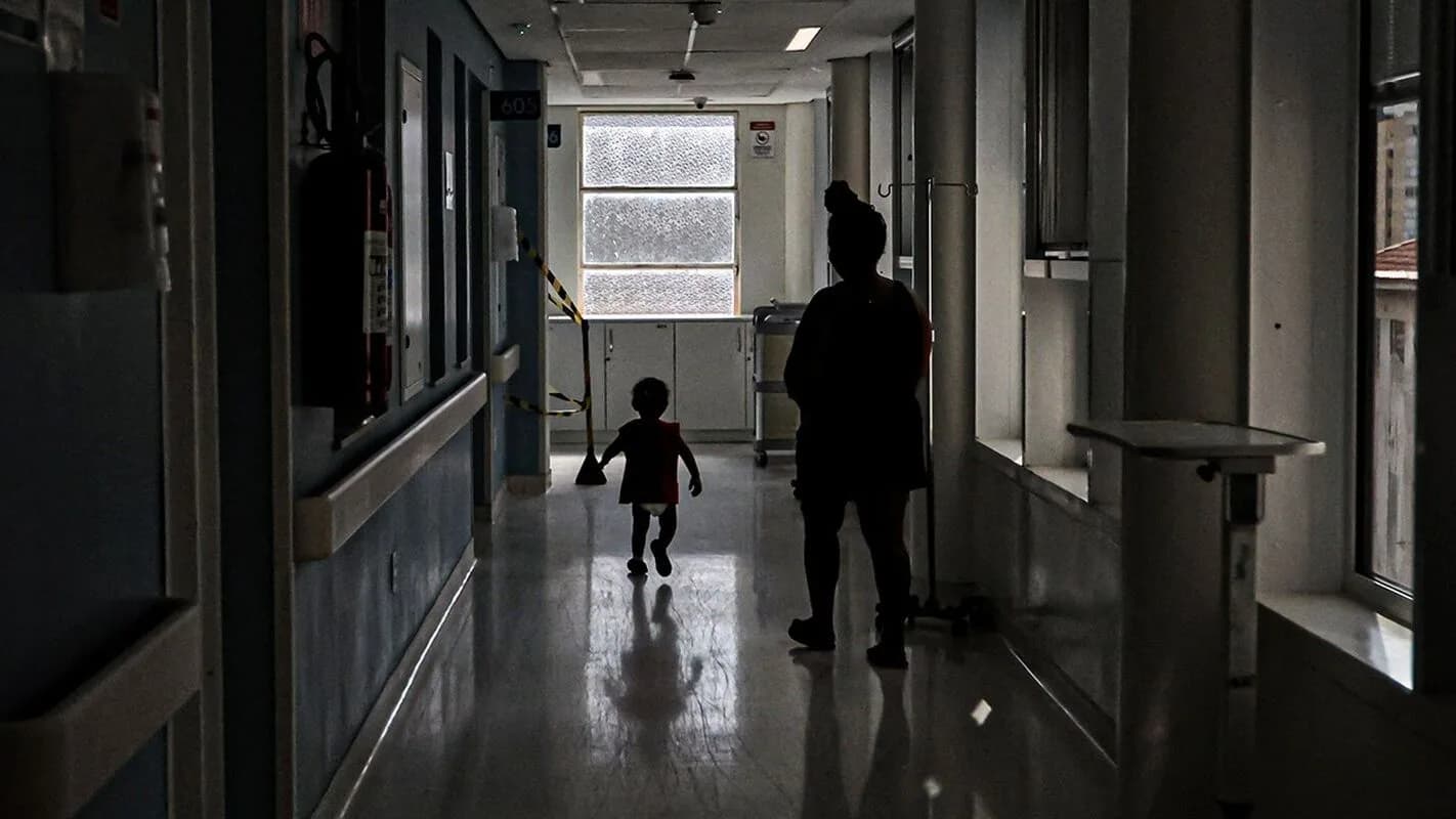 Corredor de hospital infantil com criança e acompanhante ao fundo