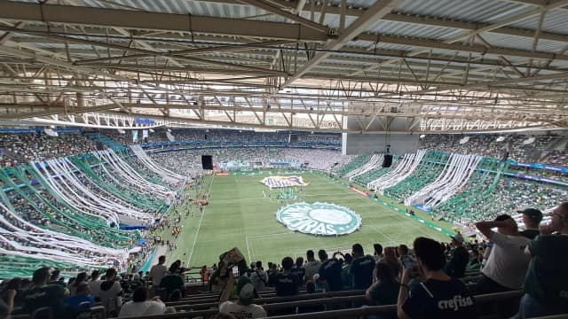 Estádio do Palmeiras lotado, com torcida usando bandeiras e faixas verdes e brancas
