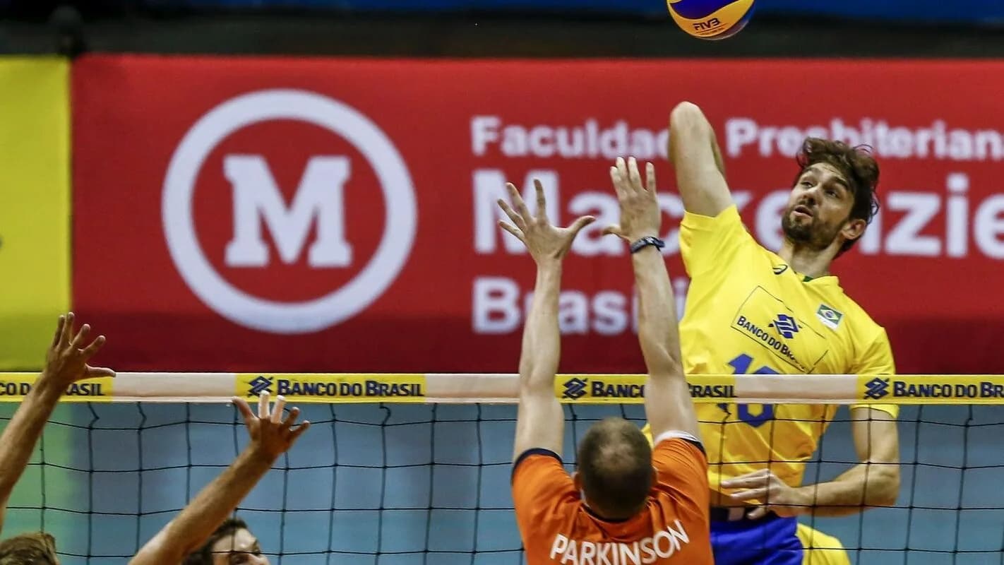 Jogadores de vôlei masculino disputam bola na rede em partida de quadra