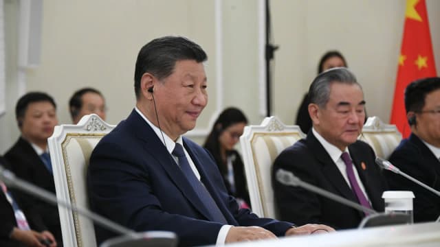 Xi Jinping em reunião de cúpula do BRICS, sentado à mesa com delegação chinesa ao fundo