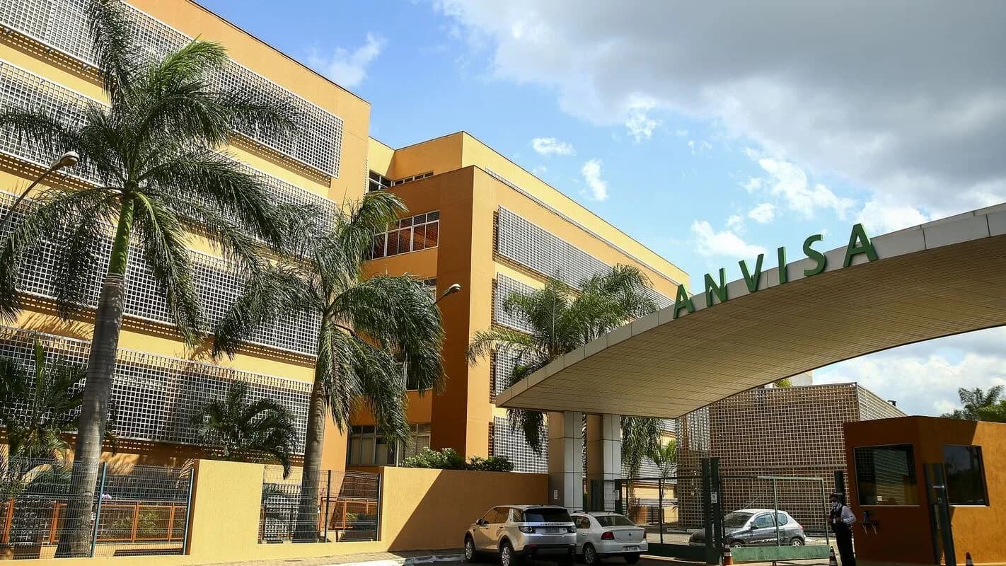 Fachada da sede da Anvisa em Brasília, com palmeiras e o letreiro verde da agência na entrada