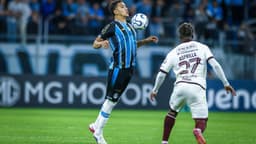 Jogador do Grêmio, de camisa tricolor, domina a bola no peito enquanto Asprilla, do Bolívar, se aproxima durante a partida na Arena