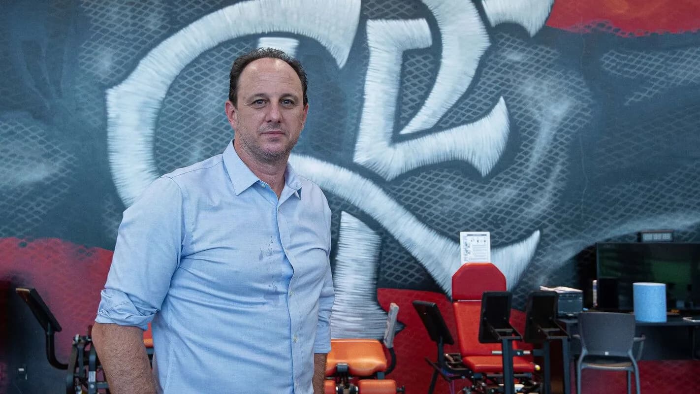 Homem de camisa azul-clara em frente a mural com o escudo do São Paulo Futebol Clube