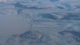 Vista aérea de gelo derretendo na costa da Groenlândia, com água visível sob a camada de gelo