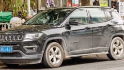 Jeep Compass preto visto de frente e lateral, em foto de arquivo