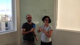 Dois profissionais discutem ideias em frente a um quadro branco em escritório