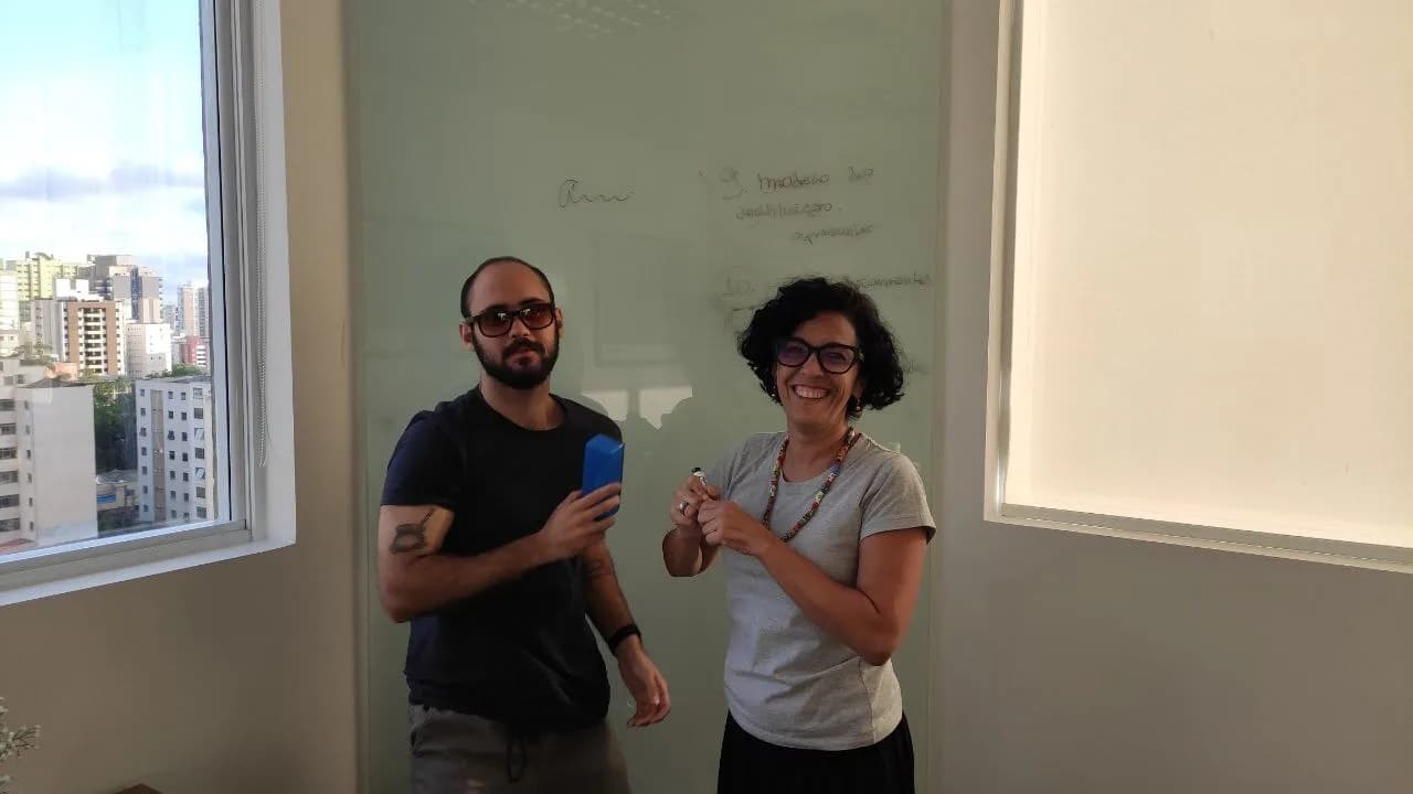 Dois profissionais discutem ideias em frente a um quadro branco em escritório