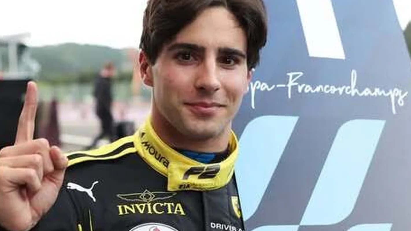 Rafael Câmara comemora com o dedo indicador erguido, vestindo macacão de corrida