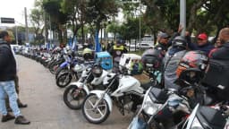 Motocicletas estacionadas com motociclistas em via pública