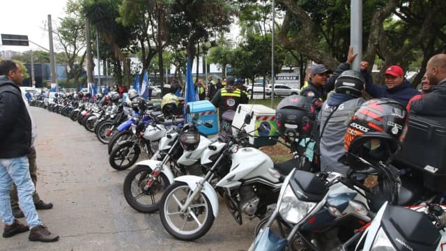 Motocicletas estacionadas com motociclistas em via pública