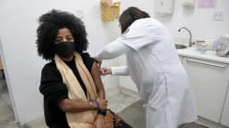 Mulher recebe dose de vacina no braço em posto de saúde