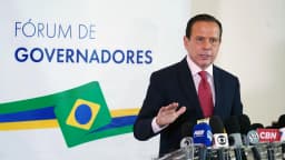 João Doria discursa em coletiva de imprensa com microfones de emissoras no púlpito do Fórum de Governadores