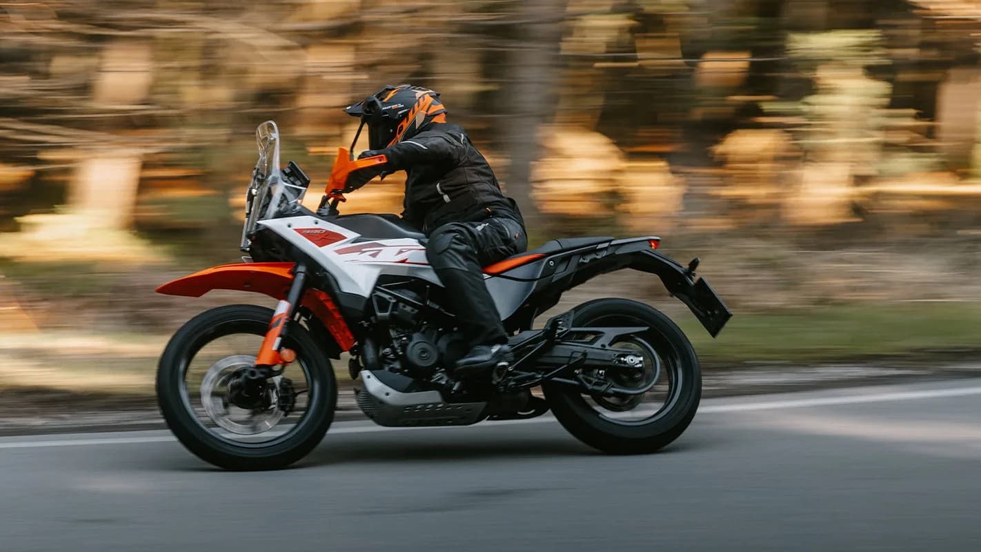 Motociclista pilota a KTM 390 Adventure X em estrada, foto de divulgação