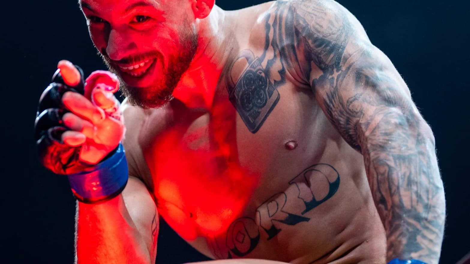 Lutador de MMA com o punho erguido durante entrada no octógono, iluminado por luz vermelha