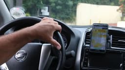 Motorista de aplicativo dirige com o celular preso ao painel do carro
