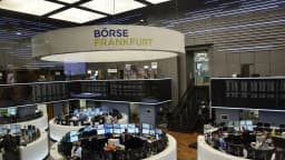 Sala de operações da Bolsa de Frankfurt, com telas de cotação e operadores trabalhando sob o letreiro Börse Frankfurt